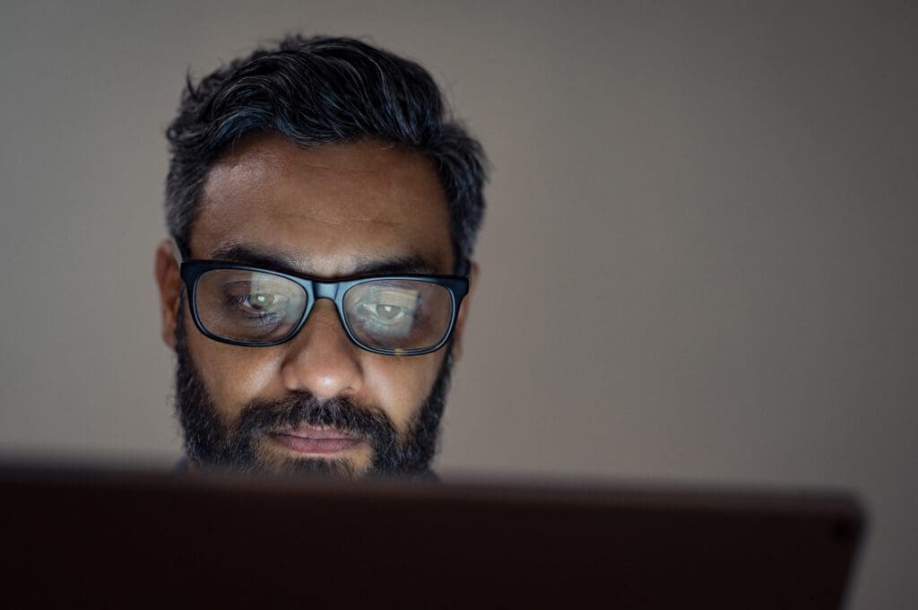 A man looks down at a laptop screen