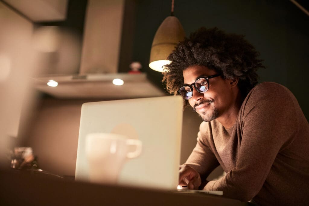 A man looks at his laptop in a dimly lit kitchen