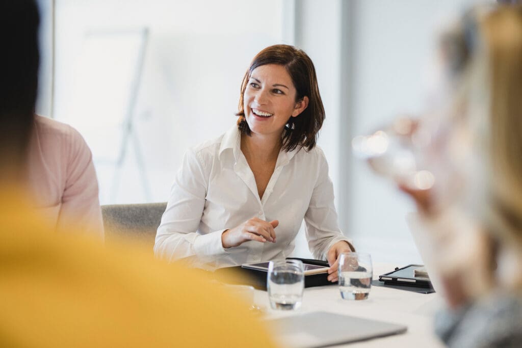 A women smiles enthusiastically in a meeting