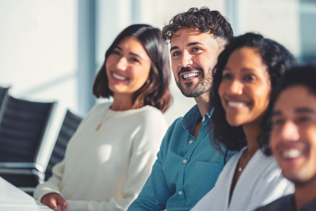 A group sit at a meeting room table smiling and listening