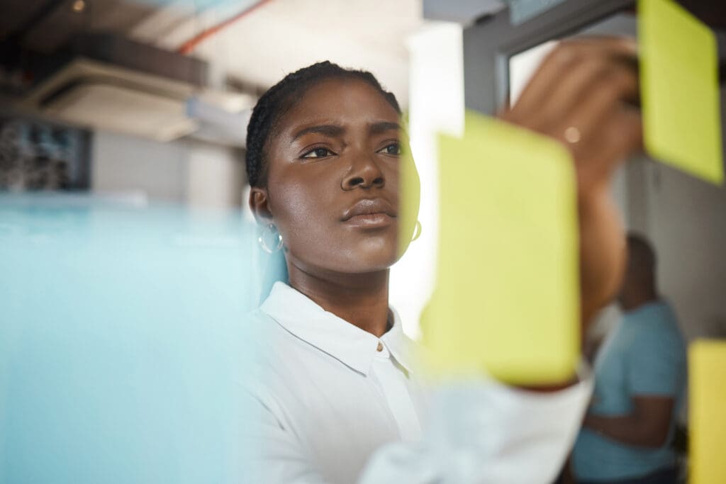 A women looks concentrated while looking at post-it notes on a wall