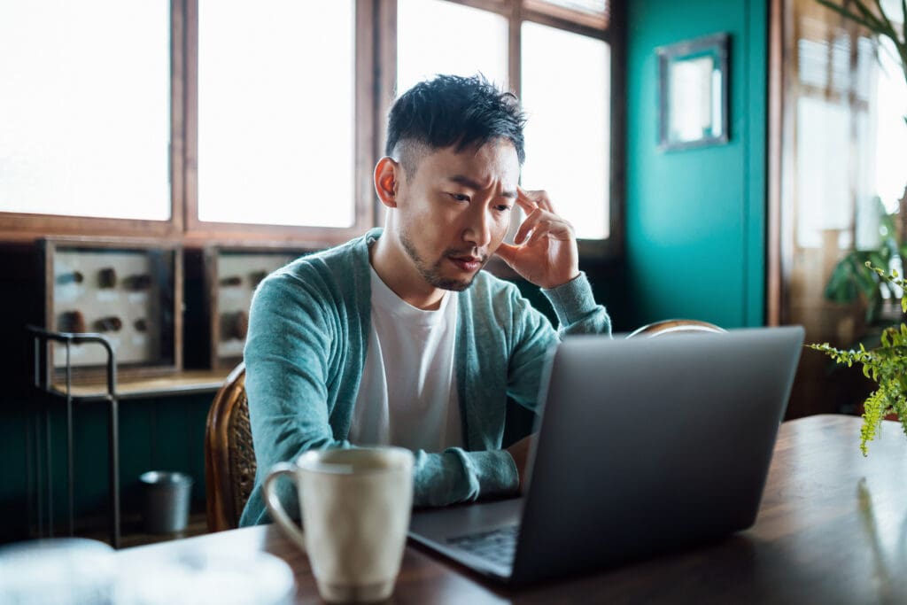 A man concentrates while looking at his laptop.