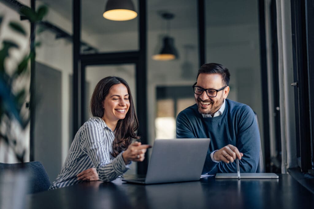 A man and a woman have a conversation while looking at a laptop