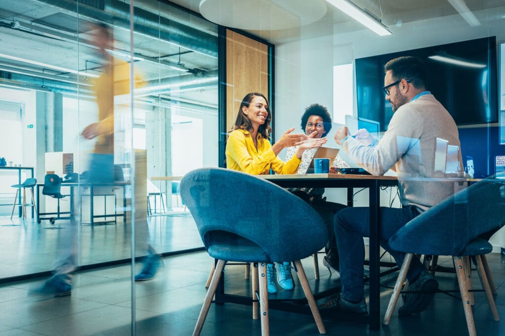 Two women and a man gather round a table and have a meeting