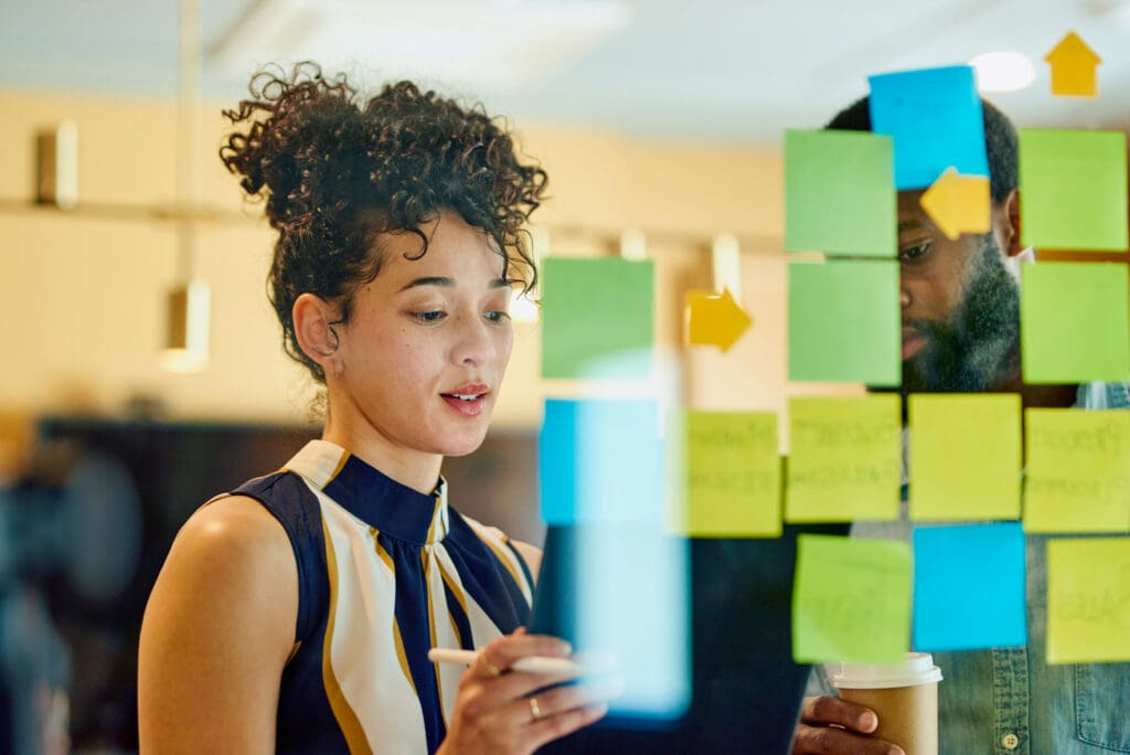 A man and a woman write on post-it notes