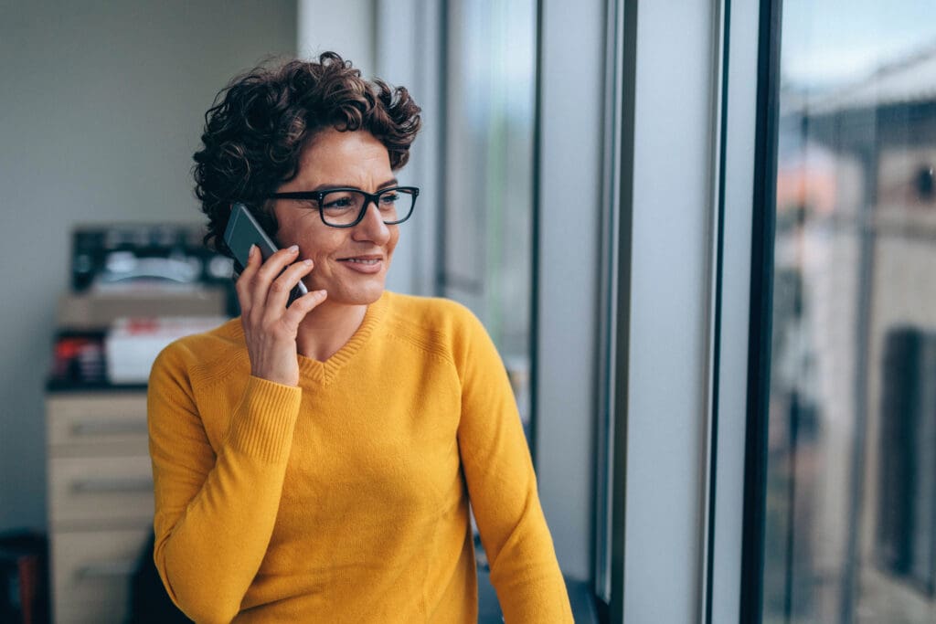 A women has a conversation on the phone while looking out a window